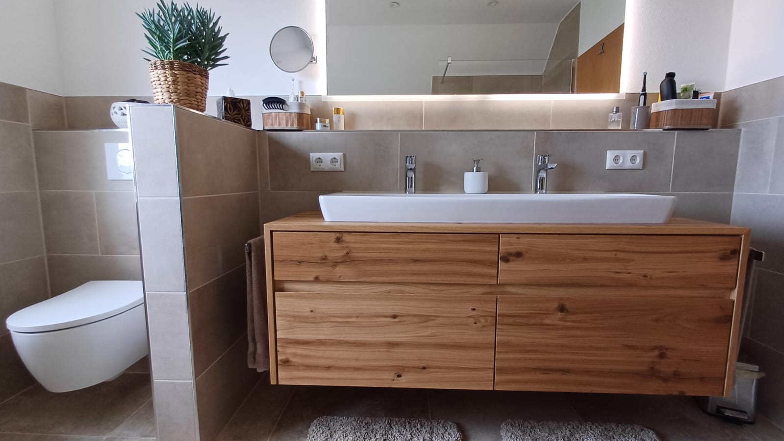 Ein modernes Badezimmer mit einem Holzwaschtisch, Waschbecken und einem WC.