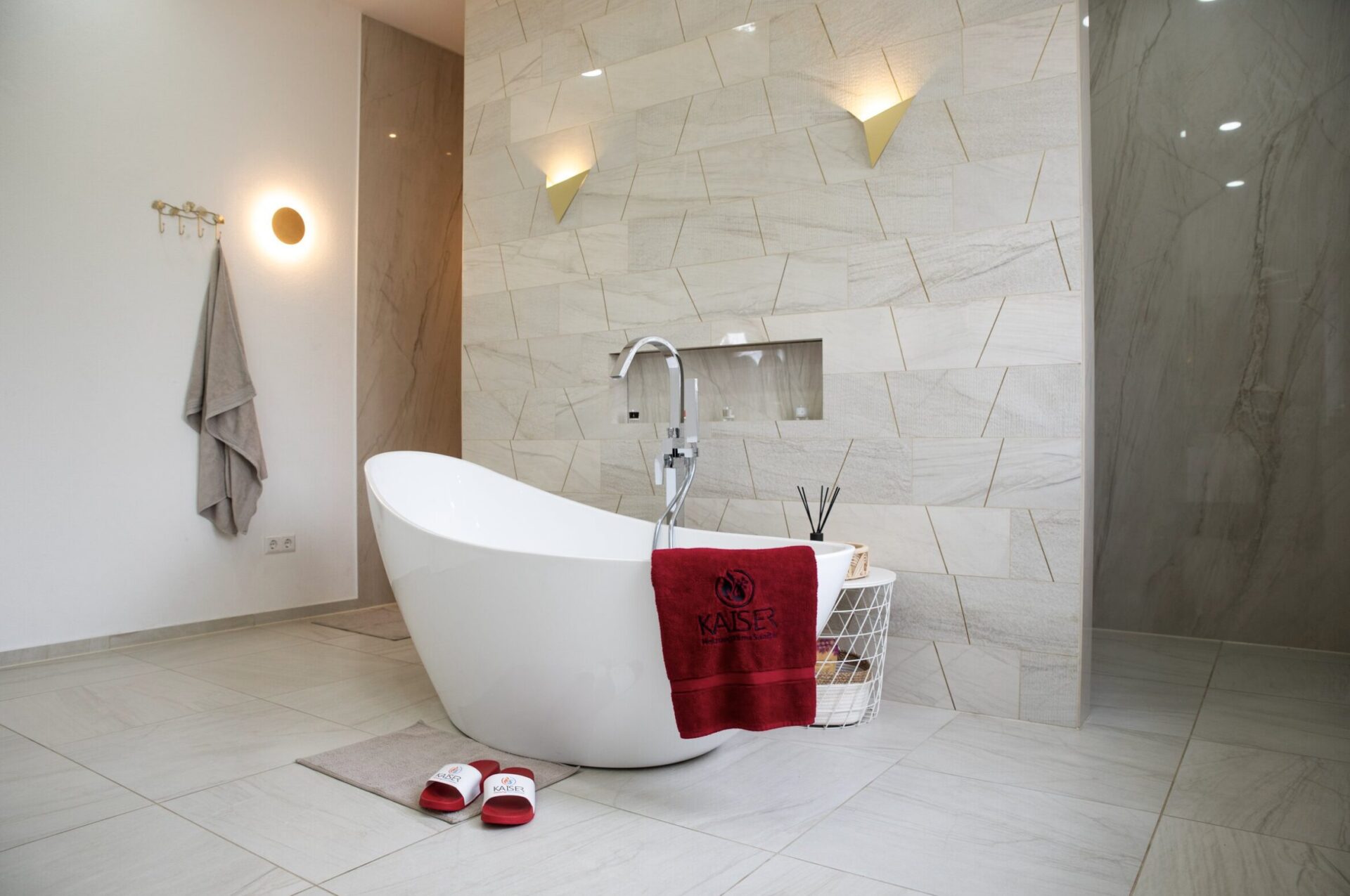Freistehende weiße Badewanne mit rotem Handtuch und Badematten im Badezimmer.