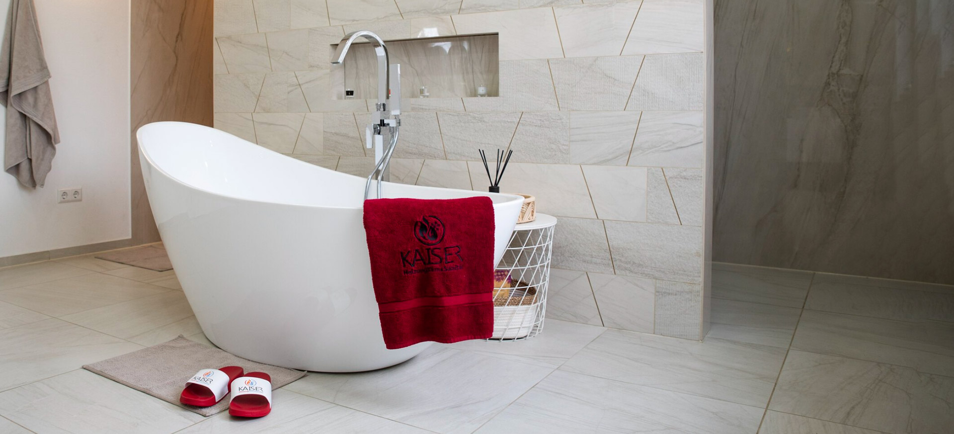 Freistehende weiße Badewanne mit rotem Handtuch und Badematten im Badezimmer.